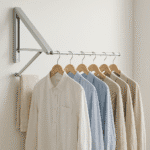 Colgador de ropa plegable instalado en una pared de hogar moderno, con prendas colgadas y espacio optimizado